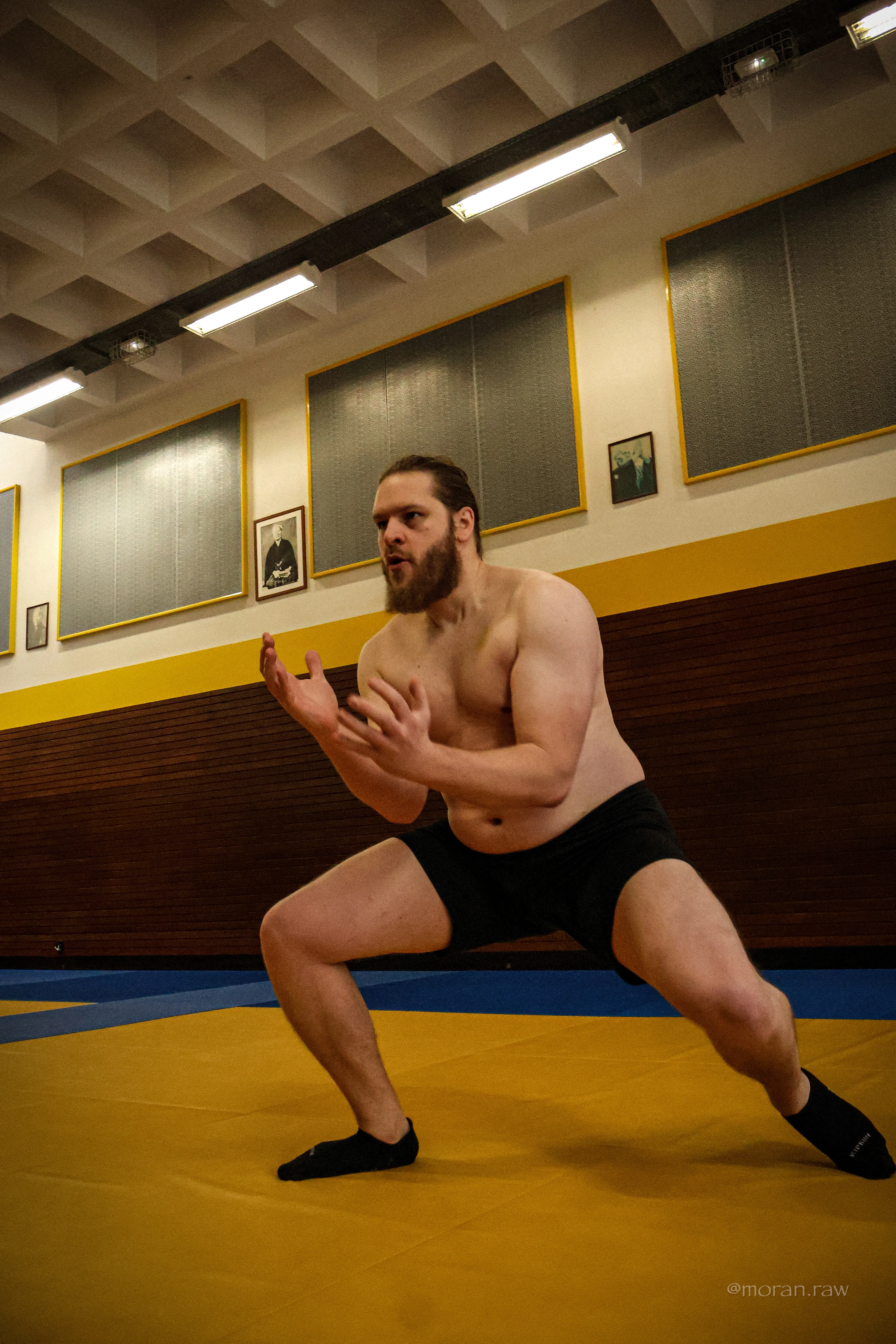 Photo d'un homme se déplaçant sur des tatamis dans une position proche du squat